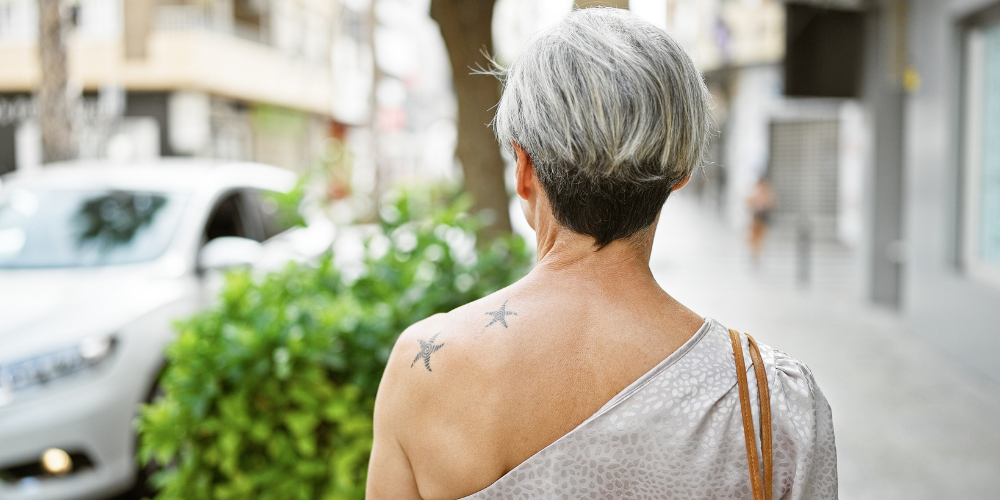 Woman with short hair and a tattoo walks down a city street.