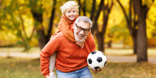 Grand-père jouant au soccer à l’extérieur avec son petit-fils.
