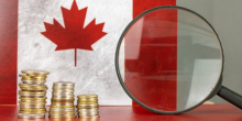 A magnifying glass with a Canadian flag and coins.