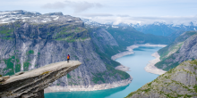 Un randonneur se tenant debout au bord de l’éperon rocheux de Trolltunga, en Norvège.